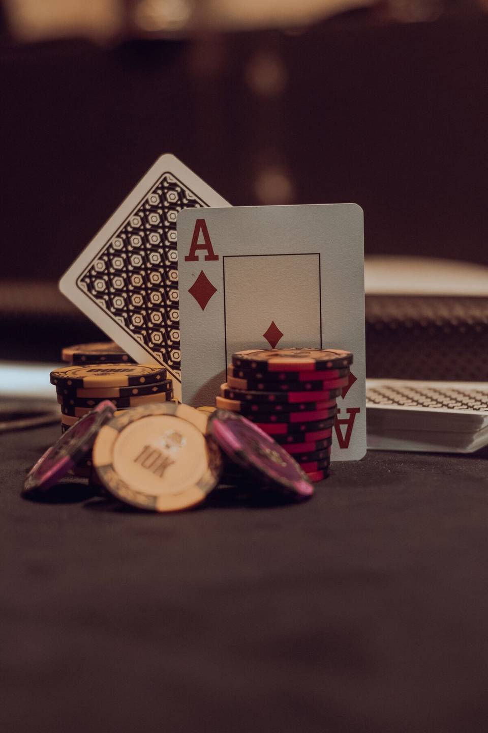 Duas cartas, um ás de copas e um ás de ouros, encostadas a pilhas de fichas